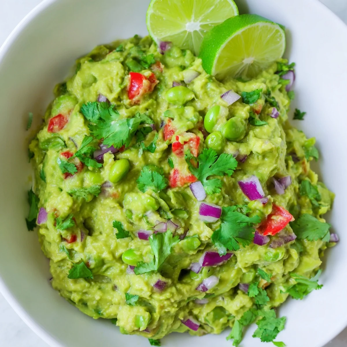 Fresh, chunky Edamame Guacamole bursting with color from red onion, tomatoes, and cilantro, delicious!