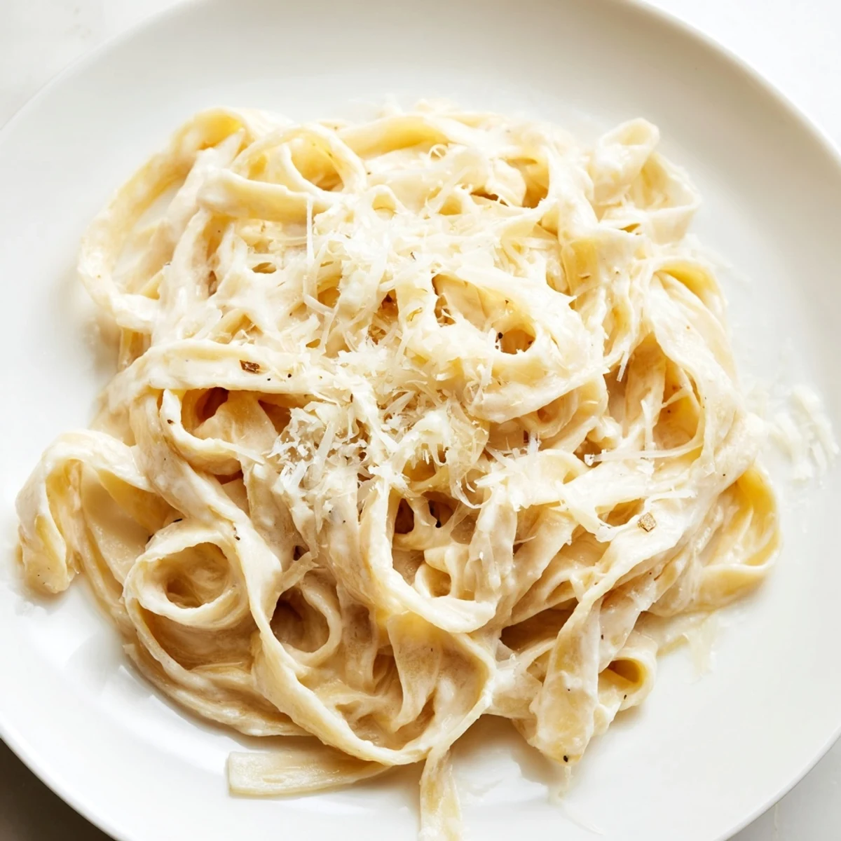 Al dente fettuccine in Roasted Garlic Cream Pasta, garnished with fresh parsley and a generous sprinkle of Parmesan.  