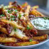 Cheesy BBQ Fries with Ranch Dip piled high with bubbly melted cheese, served alongside a creamy, homemade ranch dip.