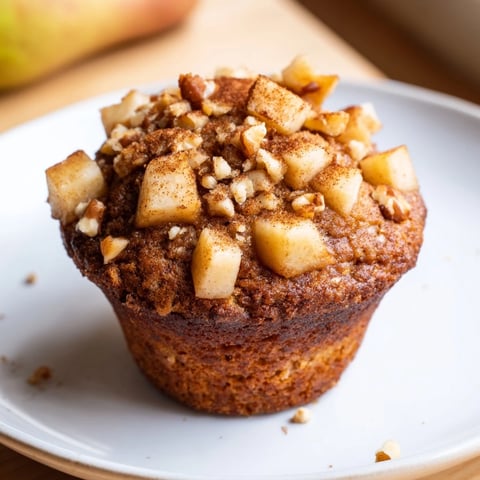 Warm, fluffy Seasonal Spiced Pear and Walnut Muffins, dotted with fruit and nuts, ready to enjoy.