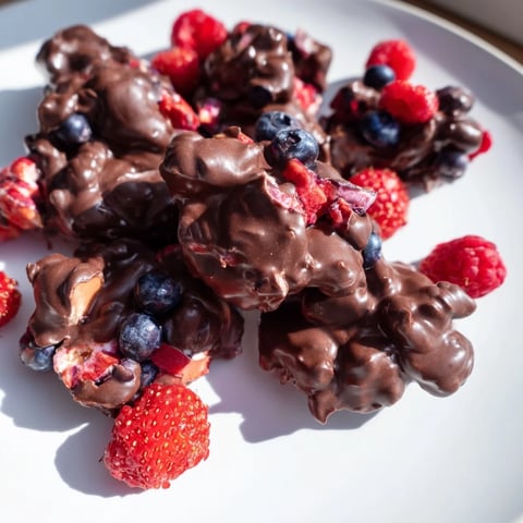 Frozen Chocolate Yogurt Clusters ready to eat, featuring a delicious mix of dark chocolate and fresh berries.
