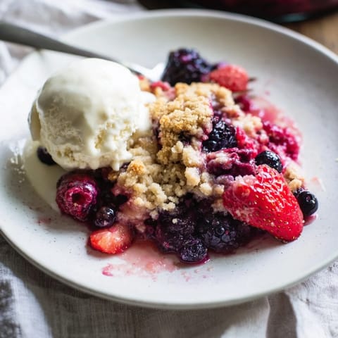 A close-up of a Rustic Summer Berry Cobbler, showing the juicy berry filling and flaky crust.