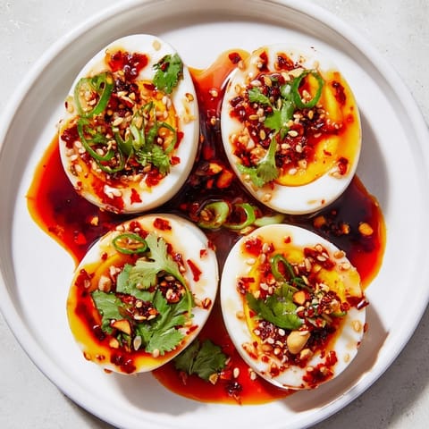 A close-up of Chili Oil Eggs, the spicy chili oil glistening over perfectly cooked yolks.