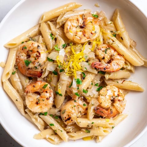 A close-up shot of steaming garlic shrimp penne, showcasing tender shrimp and flavorful sauce.