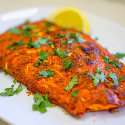 A flavorful Indian Tikka Salmon dish, with vibrant red-orange marinade coating tender salmon.