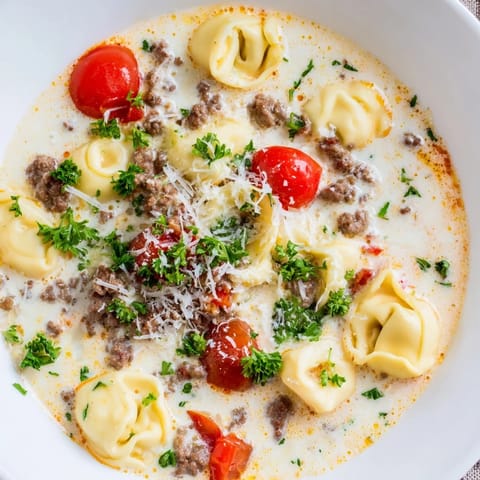Creamy Tortellini Beef Soup topped with fresh basil and Parmesan, served alongside crusty bread for dipping into the savory broth.