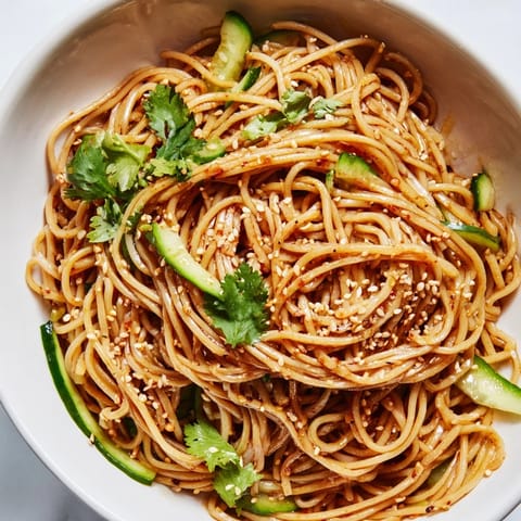 Spicy Sesame Noodle Salad topped with fresh cilantro and chopped peanuts, served chilled in a white ceramic bowl.