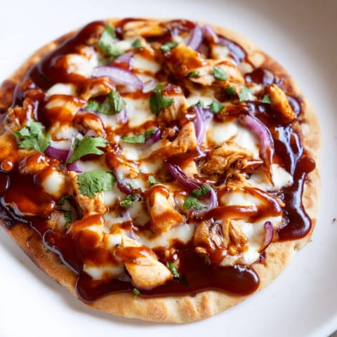Golden, bubbly BBQ Chicken Flatbread sliced into wedges, topped with tangy sauce drizzle and fresh cilantro.