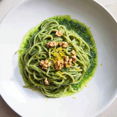 Creamy Spinach Walnut Pasta served in a white bowl, with silky green sauce coating al dente pasta and garnished with extra toasted walnuts and fresh lemon zest.