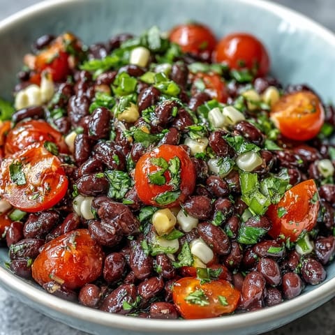 A colorful bowl of Cowboy Caviar featuring black beans, corn, and diced peppers with a zesty lime dressing, served with tortilla chips.