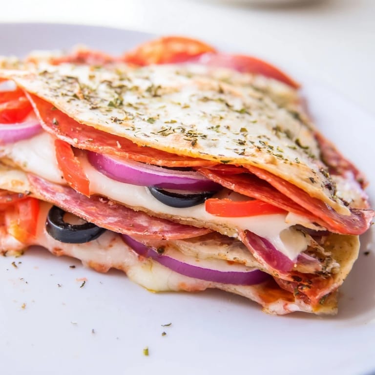A halved Tortilla Pizza Wrap served on a plate with a side salad, showcasing a crispy, layered triangle shape.