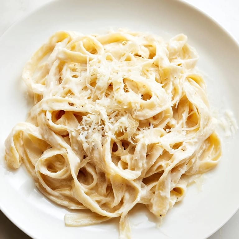 Al dente fettuccine in Roasted Garlic Cream Pasta, garnished with fresh parsley and a generous sprinkle of Parmesan.  