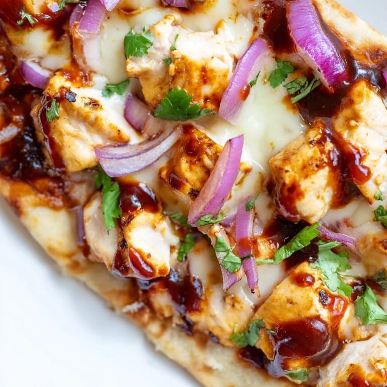 Cheesy BBQ Chicken Flatbread fresh from the oven, served on a rustic board with scattered red onions.