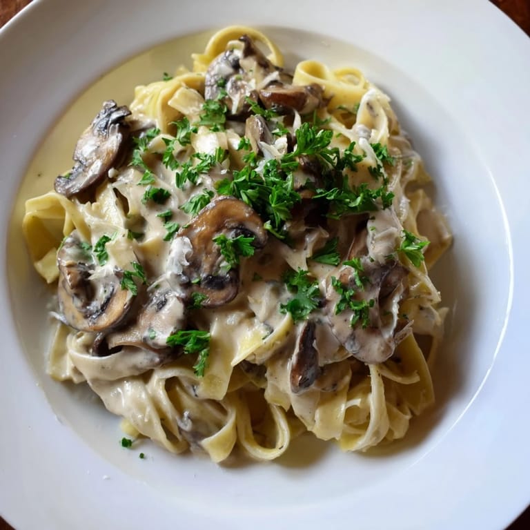 A comforting plate of homemade creamy mushroom Alfredo, ready to enjoy with a glass of white wine.