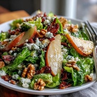 Fresh frisée salad with sweet pear slices, crumbled blue cheese, and crispy prosciutto pieces tossed in a light vinaigrette.
