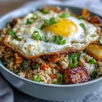 Spicy, savory Fermented Cabbage Kimchi Fried Rice Bowl with sunny-side-up egg topping.